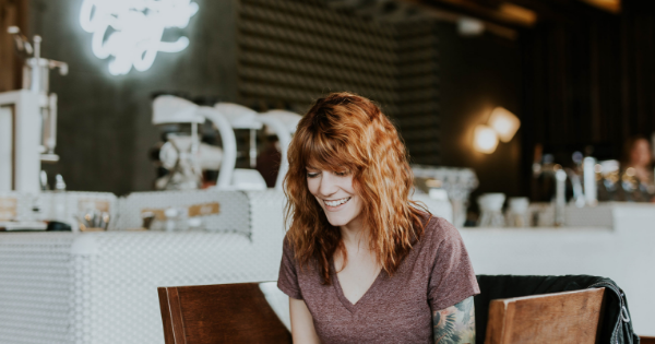 Jeune femme rousse souriante assise dans un café