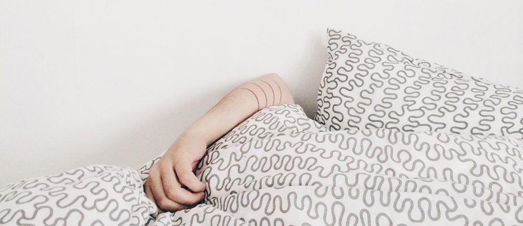 Main sortant d'un duvet sur un lit