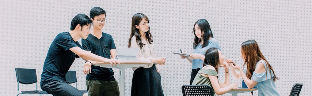 Groupe d'employés asiatiques qui discutent de leurs projets dans une aire commune