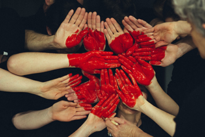 peinture rouge appliquée sur un groupe de mains pour former un coeur