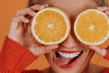 Femme qui tient des tranches d'orange devant ses yeux